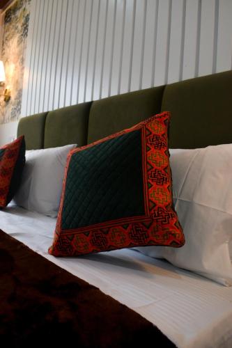 a bed with a green headboard and pillows on it at The Himalayan Roots in Kulu