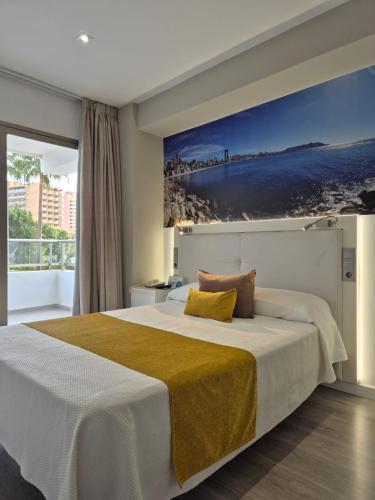 a bedroom with a large bed with a painting on the wall at Flamingo Beach Resort - Adults Recommended in Benidorm