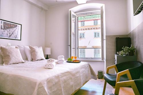 a bedroom with a white bed with a chair and a window at Stradun Main Street Residence in Dubrovnik