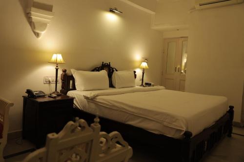 a bedroom with a bed with two lamps and a phone at Chirmi Palace - A Heritage Home in Jaipur