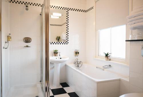 a white bathroom with a sink and a tub and a sink at Arbutus Hotel in Killarney