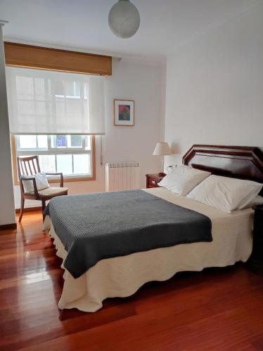 a bedroom with a large bed and a chair at Centro1 in Vilagarcia de Arousa