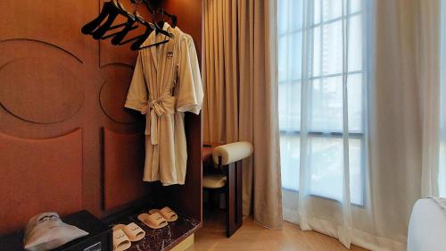 a room with a robe and shoes on a wall at Marwin Monique Hotel in Bangkok