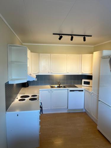 a white kitchen with white cabinets and a sink at Leilighet i Vadsø in Vadsø