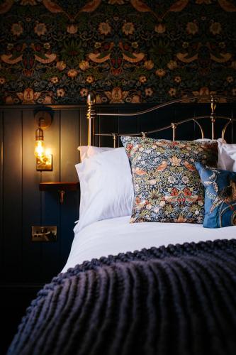 a bedroom with a bed with pillows and a wall at Bronte's Rest - Detached Elegant Cottage in Historic Old Town with Garden in Scarborough