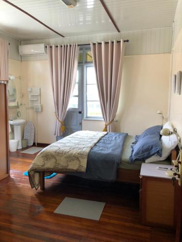 a bedroom with a bed and a window with curtains at staylikehome guesthouse in Nieuw Nickerie