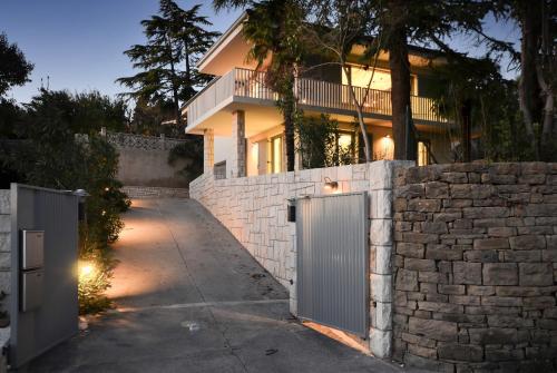 a house with a stone wall and a gate at Forgotten Garden Villa in Portorož