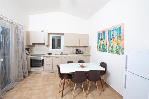 a white kitchen with a table and chairs in it at Scorpina Horizon Villa in Kalamitsi