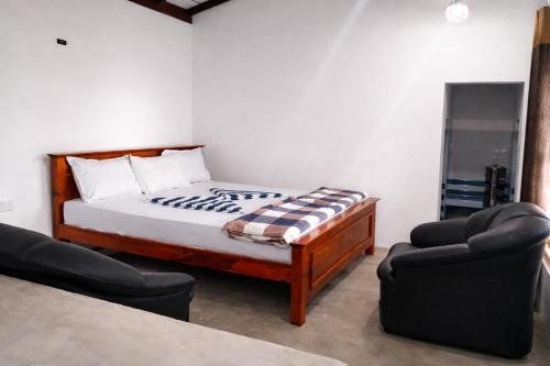 a bedroom with a bed and two chairs at Hill House Haldummulla in Badulla