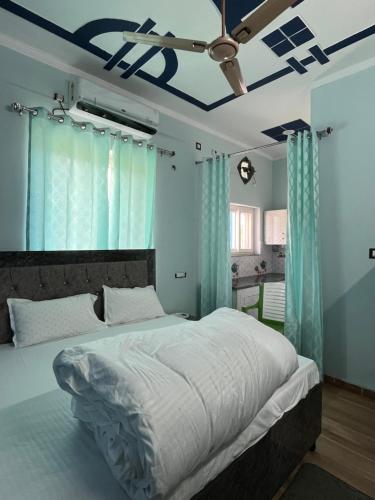 a bedroom with a large bed with blue curtains and a ceiling at Bhadraj Valley Homestay in Dehradun