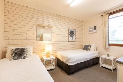a bedroom with two beds and a mirror at Reef Villa- Kalbarri Central with Pool in Kalbarri