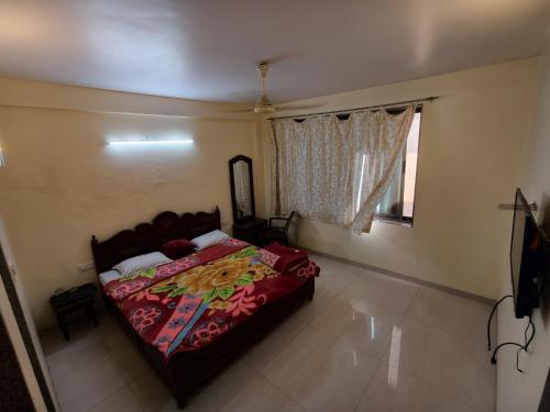 a bedroom with a bed with a red blanket and a window at Salas Executive in Mahabaleshwar