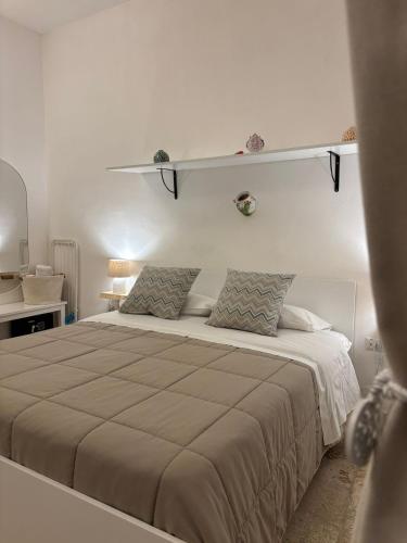 a white bedroom with a large bed with two pillows at Dioniso Affittacamere in Conversano