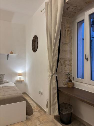 a white bedroom with a bed and a window at Dioniso Affittacamere in Conversano