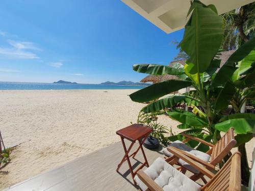 a beach with two chairs and a view of the ocean at Ocean Breeze Bungalow in Sông Cầu