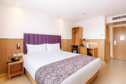 a bedroom with a large bed with a purple headboard at Eurotraveller Hotel - Premier - Tower Bridge in London