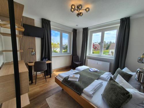 a bedroom with a bed and a desk and windows at Seehaus Miersdorf in Zeuthen