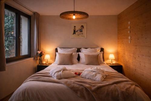 a bedroom with a large bed with two pillows at L'Impasse en Duo, appartement cosy 2 personnes avec SPA extérieur privé in Munster