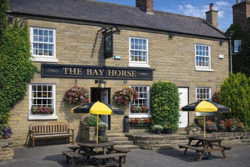 a inn with two tables and two umbrellas in front of it at The Bay Horse Country Inn in Thirsk