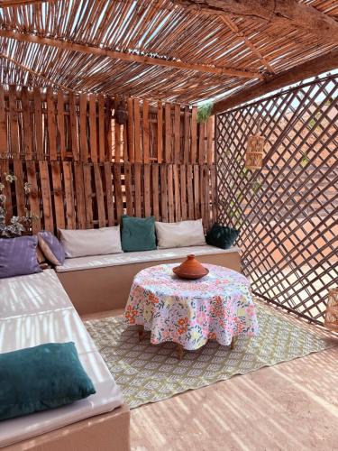 a room with a table and a bench in a straw hut at RiadTiznitSouss Votre oasis privée à Tiznit in Tiznit