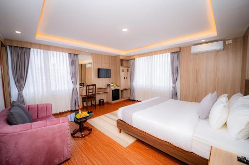 a bedroom with a white bed and a pink couch at Hotel Sampada Boutique in Pokhara