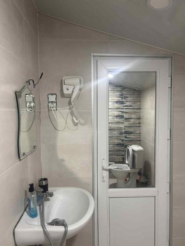 a white bathroom with a sink and a mirror at ksenia apartment in Borjomi