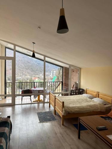 a bedroom with a bed and a large window at ksenia apartment in Borjomi