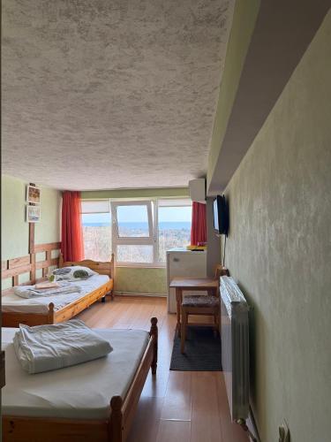 a room with two beds and a desk and a television at Villa Climate Guest House in Varna City