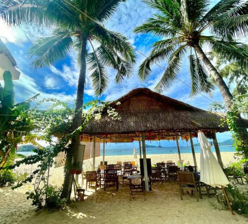 a restaurant on the beach with palm trees at Ocean Breeze Bungalow in Sông Cầu