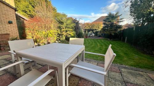 a white table and chairs in a yard at Superb Comfy 2 Bed House, Responsive & Caring Hosts Free WiFi & Parking, Close to MK Centre, Train Station, Santander, Network Rail by Webbhill Stays in Milton Keynes