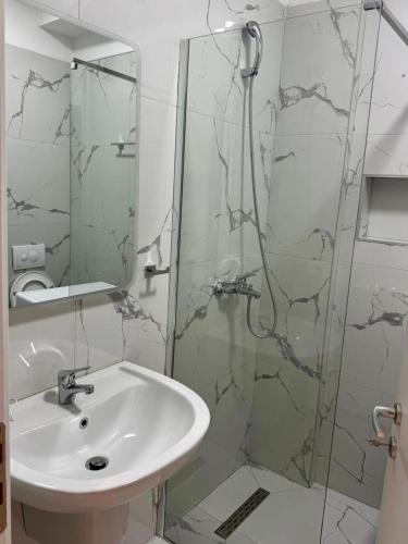 ein Badezimmer mit Waschbecken und Glasdusche in der Unterkunft M&I Apartment in Sarandë