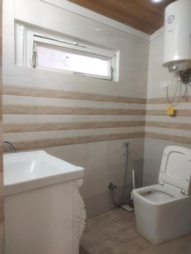 a bathroom with a white toilet and a window at HideOut The Mall in Shimla