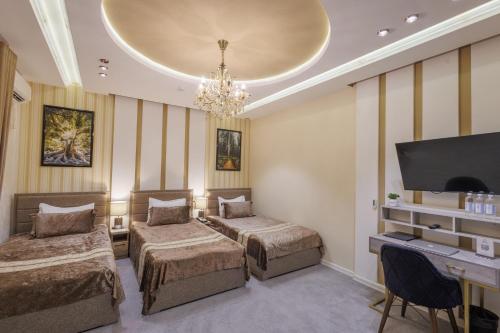 ein Hotelzimmer mit zwei Betten und einem Flachbildfernseher in der Unterkunft Fergana hotel in Fargʻona