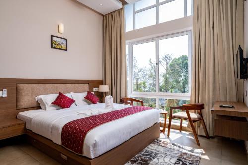 a bedroom with a bed and a large window at THRILL HOLIDAYS MUNNAR in Anachal