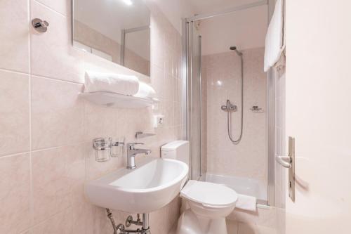 a bathroom with a sink and a toilet and a shower at Hotel Atlantico self check-in in Lugano