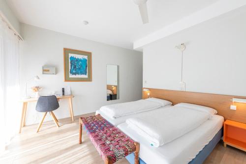 a white bedroom with two beds and a table at Hotel Atlantico self check-in in Lugano