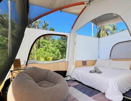 ein Schlafzimmer in einem Zelt mit einem Bett und einem Stuhl in der Unterkunft Camp Laya Daracoton Island in El Nido