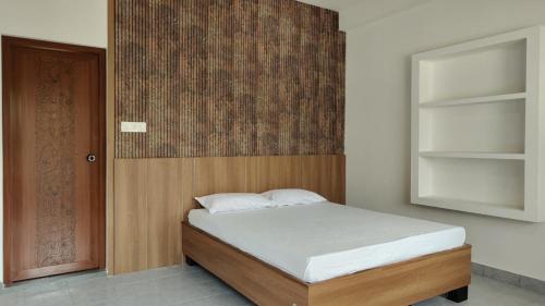 a bedroom with a bed with a wooden headboard at Noble Darshan in Guruvāyūr