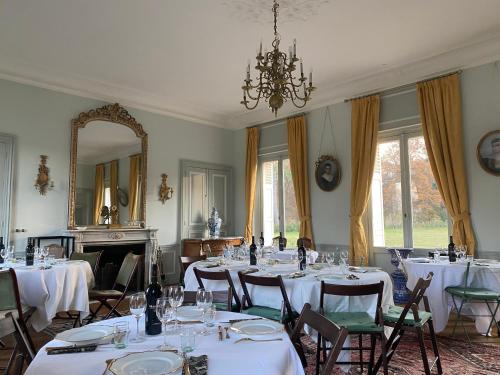 a dining room with white tables and chairs and a mirror at Chateau le Quesnoy in Chevrières