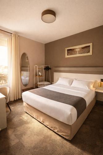 a bedroom with a large bed and a window at LOGIS Hotel Majestic Chatelaillon Plage - La Rochelle in Châtelaillon-Plage