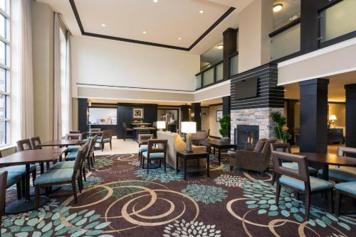 a lobby with tables and chairs and a fireplace at Staybridge Suites Chicago-Oakbrook Terrace by IHG in Oakbrook Terrace