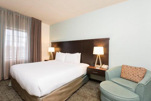 a hotel room with a bed and a chair at Staybridge Suites Chicago-Oakbrook Terrace by IHG in Oakbrook Terrace