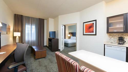 a hotel room with a desk and a room with a bed at Staybridge Suites Chicago-Oakbrook Terrace by IHG in Oakbrook Terrace