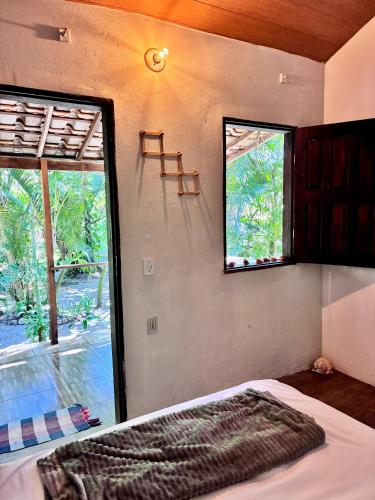 a bedroom with a bed and a large window at Mar de Moreré in Cairu