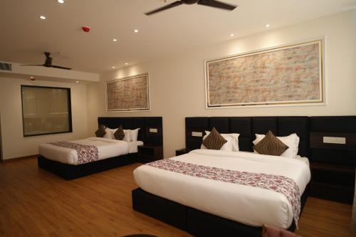 a hotel room with two beds and a ceiling fan at ACR Luxury Hotel in Mohali