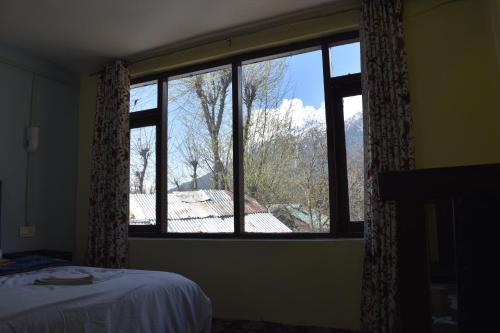 a bedroom with a window with a view of a roof at Dreamland Cottage in Pahalgām