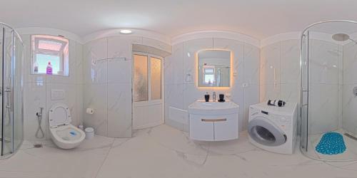 a white bathroom with a sink and a toilet at Apartment Darlin Berat in Berat