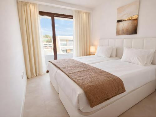 a bedroom with a white bed with a large window at Eden50 in Mijas Costa