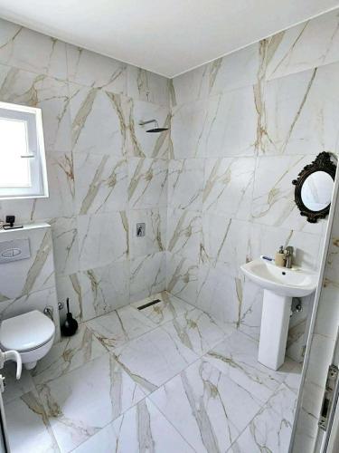 a white bathroom with a sink and a toilet at Veloura in Ulcinj