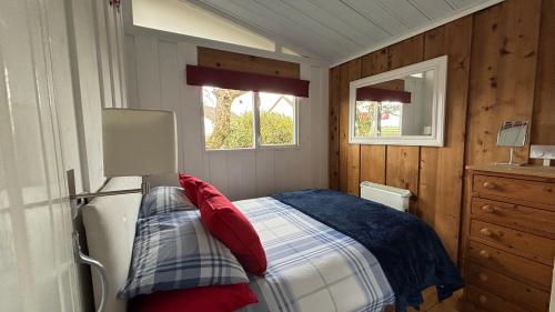 a small bedroom with a bed and two windows at Chalet 24 in Seaton